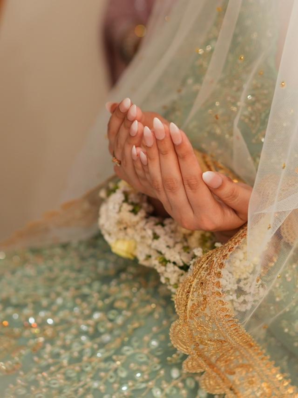 Soft nude-to-white ombre bridal press-on gel nails, worn by a bride with a mint-and-gold dupatta over folded hands, luminous Valima reception palette