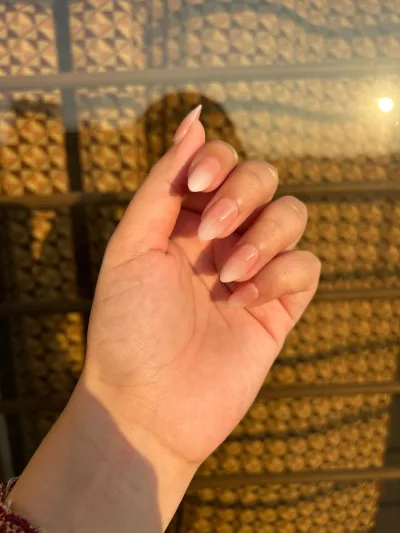 Long almond nude ombre press-on nails in warm evening light